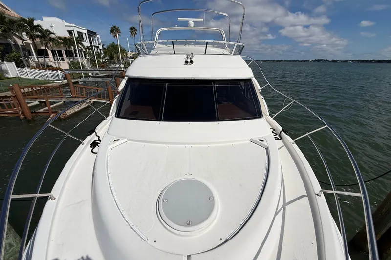 Slide: The Image of 2004 Silverton 43 Motor Yacht docked by waterfront homes under a blue sky. - 56