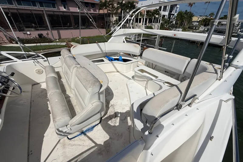 Slide: The Image of 2004 Silverton 43 Motor Yacht with spacious seating area and helm, docked by waterfront homes. - 64