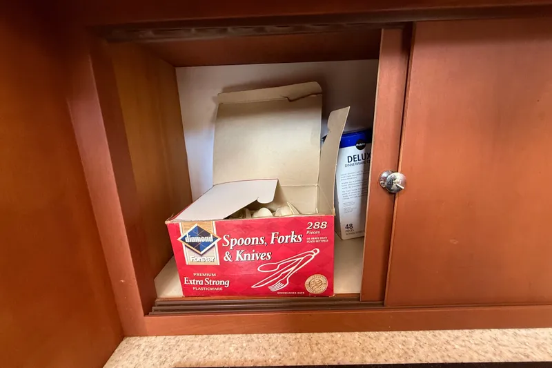 Slide: The Image of Box of plastic cutlery in a wooden cabinet on a 2004 Silverton 43 Motor Yacht. - 99