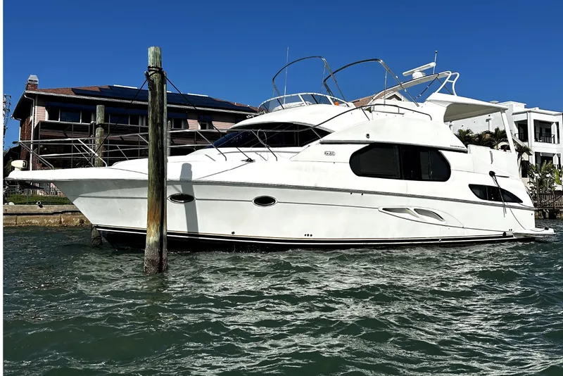Slide: The Image of 2004 Silverton 43 Motor Yacht docked by waterfront homes under clear blue sky. - 4