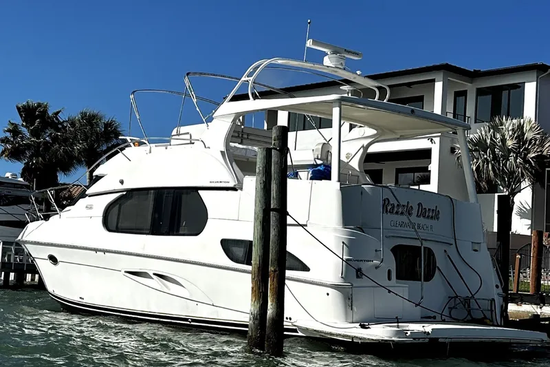 Slide: The Image of 2004 Silverton 43 Motor Yacht docked by waterfront homes under clear blue sky. - 3