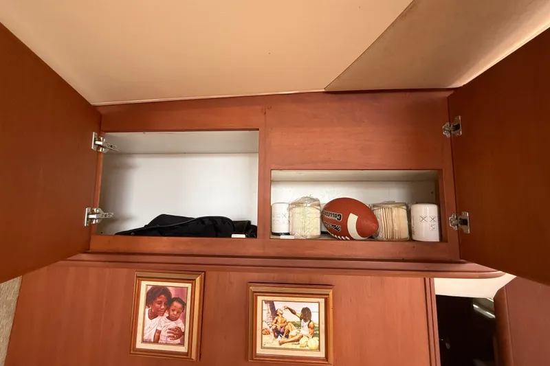 Slide: The Image of Upper cabinet storage in 2004 Silverton 43 Motor Yacht with football and framed photos. - 137