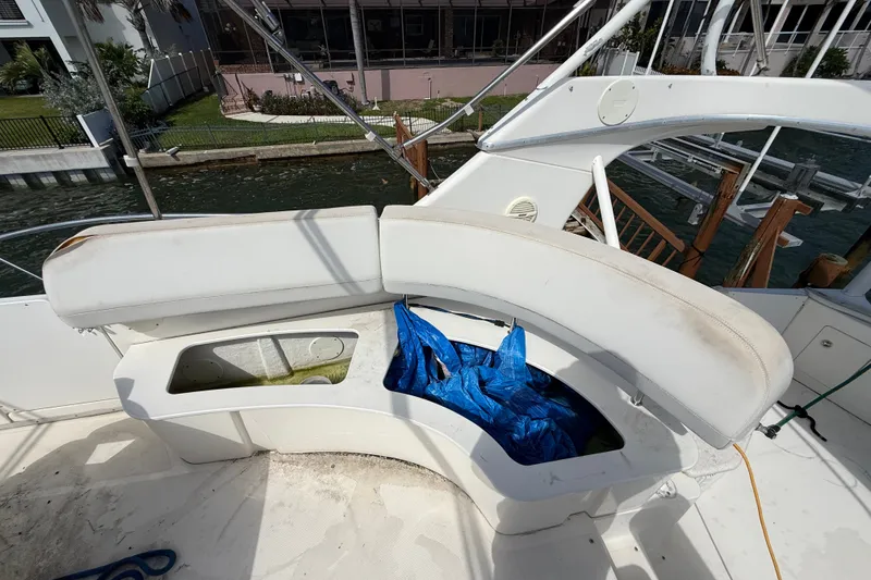 Slide: The Image of 2004 Silverton 43 Motor Yacht seating area with storage compartment and blue tarp. - 21