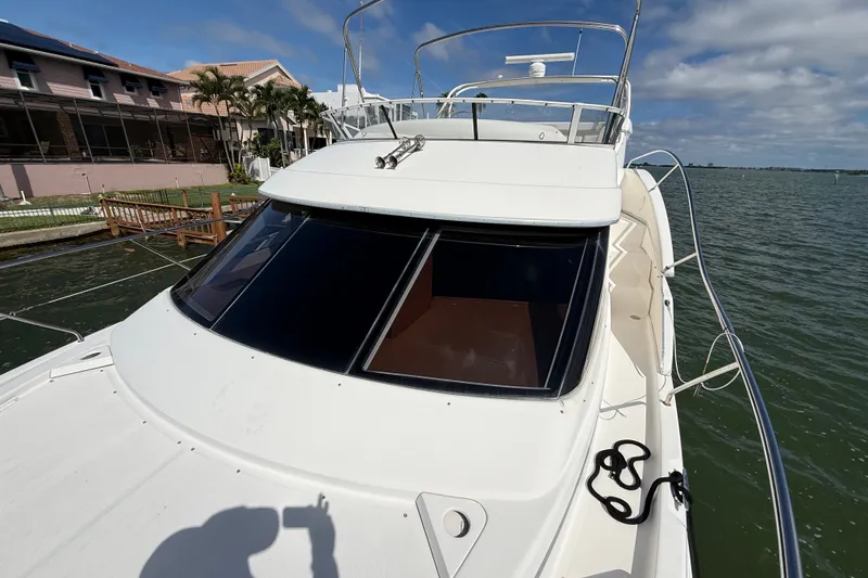 Slide: The Image of 2004 Silverton 43 Motor Yacht docked by waterfront homes under a partly cloudy sky. - 58