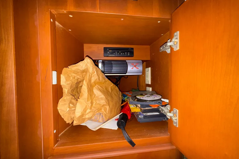 Slide: The Image of Open wooden cabinet on 2004 Silverton 43 Motor Yacht, containing miscellaneous items and electronics. - 144