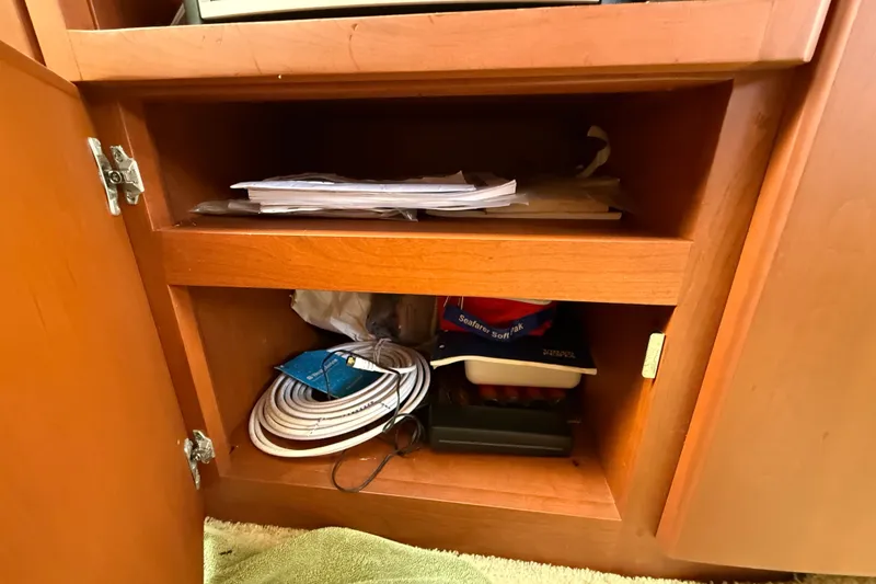Slide: The Image of Open wooden cabinet on 2004 Silverton 43 Motor Yacht, storing papers and coiled cables. - 85