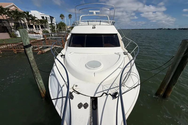 Slide: The Image of 2004 Silverton 43 Motor Yacht docked by waterfront homes under a partly cloudy sky. - 54
