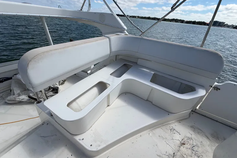 Slide: The Image of 2004 Silverton 43 Motor Yacht seating area with storage compartments, overlooking calm waters. - 17