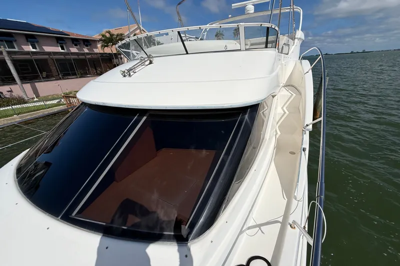 Slide: The Image of 2004 Silverton 43 Motor Yacht docked by waterfront, showcasing sleek design and spacious deck. - 59
