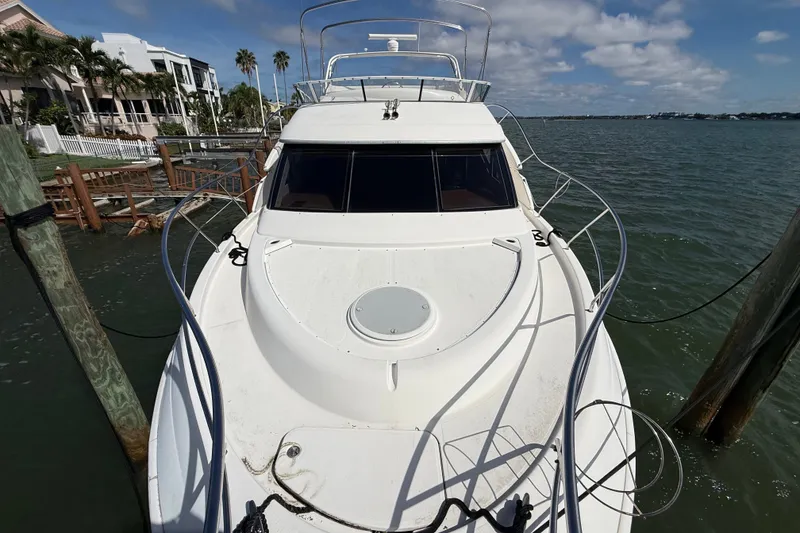 Slide: The Image of 2004 Silverton 43 Motor Yacht docked by waterfront homes under a partly cloudy sky. - 55