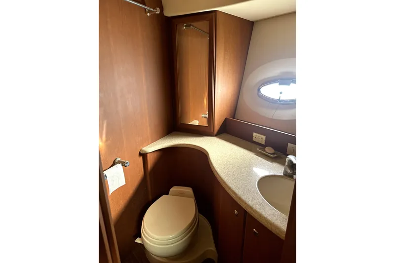 Slide: The Image of 2004 Silverton 43 Motor Yacht bathroom with wood cabinetry and oval window. - 12