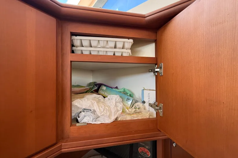 Slide: The Image of Open wooden cabinet on 2004 Silverton 43 Motor Yacht, storing miscellaneous items. - 105