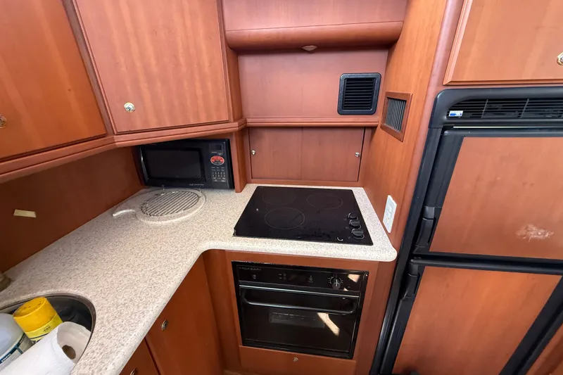 Slide: The Image of 2004 Silverton 43 Motor Yacht kitchen with stove, microwave, and refrigerator. - 97
