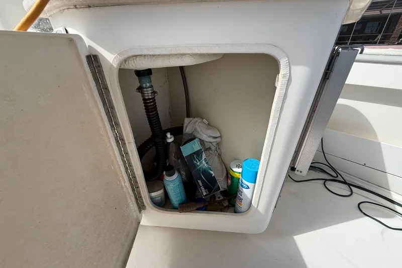 Slide: The Image of Open storage compartment on 2004 Silverton 43 Motor Yacht with cleaning supplies and hoses. - 12