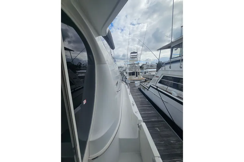Slide: The Image of 2001 Carver 564 Cockpit Motor Yacht docked alongside other boats under cloudy skies. - 29