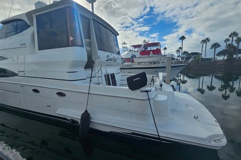 Slide: The Image of 2001 Carver 564 Cockpit Motor Yacht docked, reflecting on calm water under a partly cloudy sky. - 4