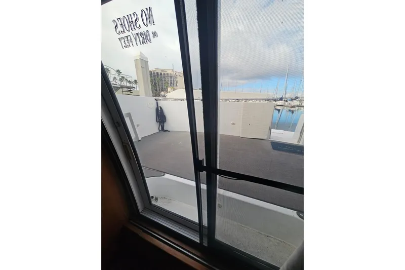 Slide: The Image of View from 2001 Carver 564 Cockpit Motor Yacht, marina in background, "No Shoes" sign visible. - 22