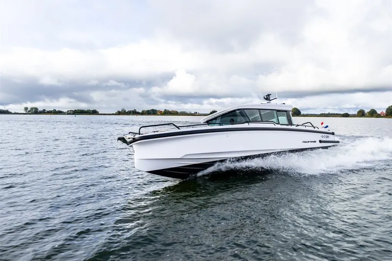 Slide: The Image of 2022 Axopar 37 XC Cross Cabin cruising on a calm lake under cloudy skies. - 1