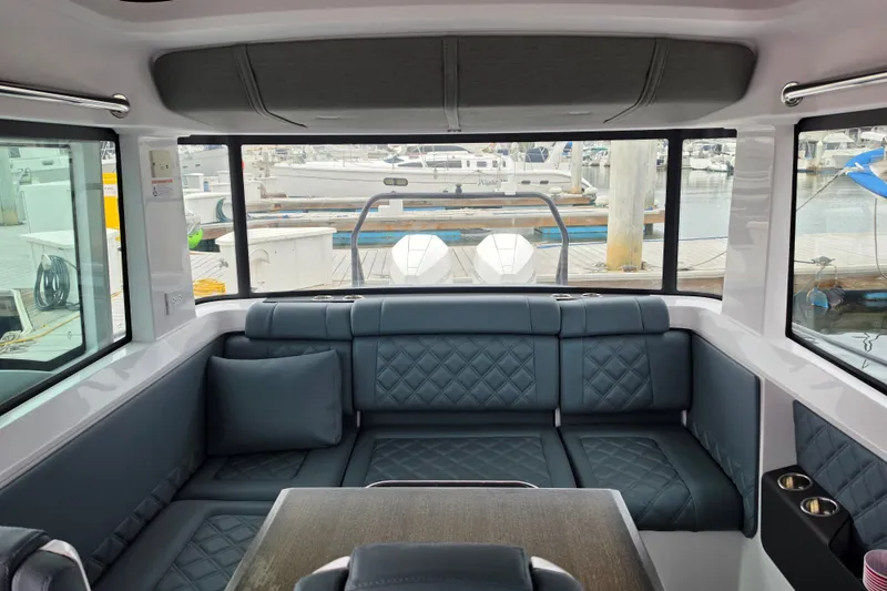 Slide: The Image of Interior of 2022 Axopar 37 XC Cross Cabin with plush seating and marina view. - 11