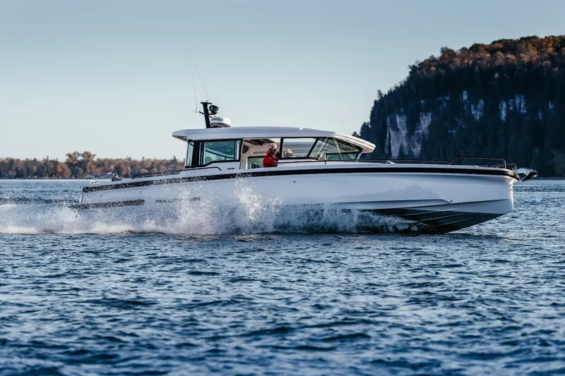 Slide: The Image of 2022 Axopar 37 XC Cross Cabin cruising on a scenic lake with forested cliffs. - 26