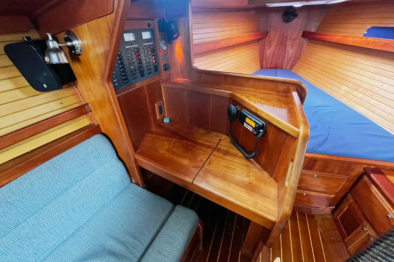 Slide: The Image of 2007 Sabre Spirit yacht interior with wooden cabinetry, control panel, and blue cushioned seating. - 32
