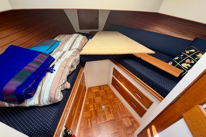 Slide: The Image of Interior cabin of a 1975 Grand Banks 32 Sedan with cozy bedding and wooden storage. - 21