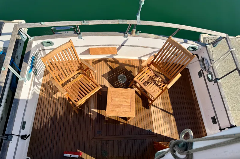 Slide: The Image of 1975 Grand Banks 32 Sedan deck with wooden chairs and table, overlooking calm water. - 5