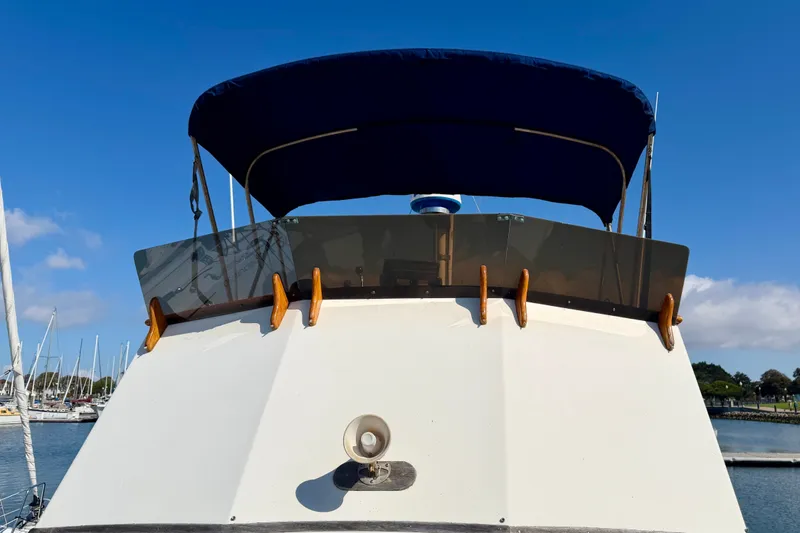 Slide: The Image of 1975 Grand Banks 32 Sedan boat with blue canopy, docked in a marina under clear skies. - 4
