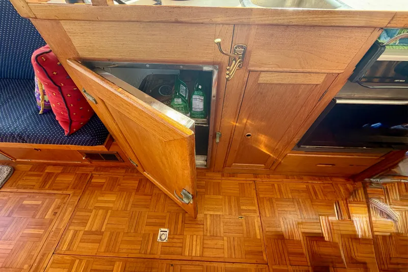 Slide: The Image of 1975 Grand Banks 32 Sedan interior with open wooden cabinet and parquet flooring. - 16