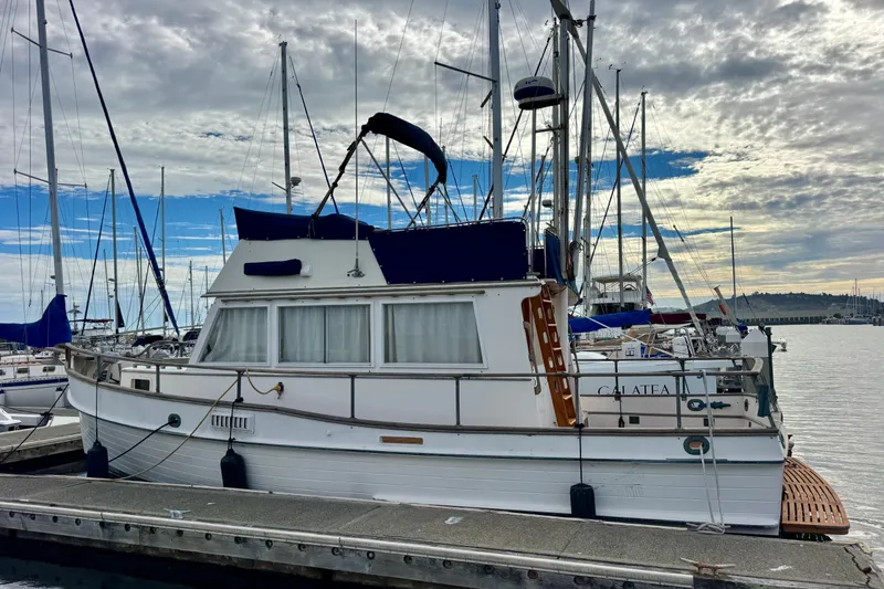 Slide: The Image of 1975 Grand Banks 32 Sedan boat docked at a marina under a cloudy sky. - 3