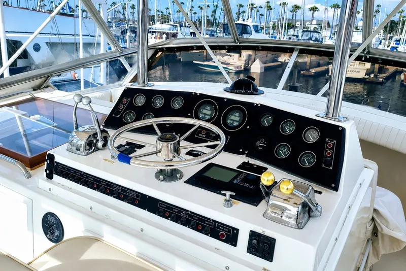 Slide: The Image of Helm of 1981 Bertram 46.6 yacht with steering wheel and control panel in marina setting. - 4