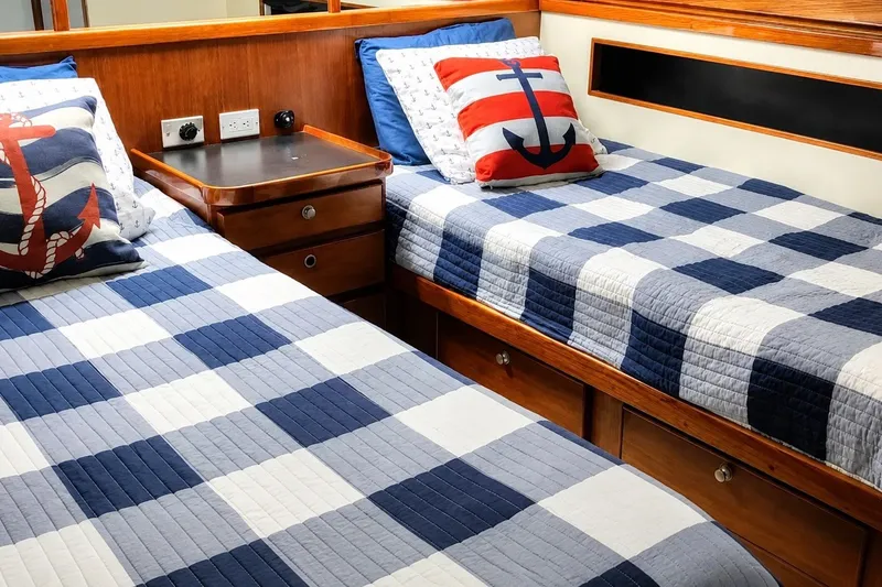 Slide: The Image of Twin beds with nautical-themed pillows in a 1981 Bertram 46.6 yacht cabin. - 18