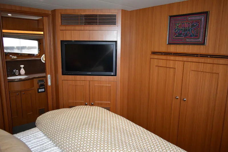 Slide: The Image of Luxurious 2011 Ocean Alexander 60 Trawler cabin with wood paneling, TV, and ensuite bathroom. - 87