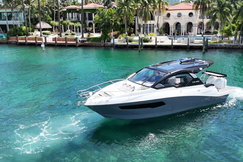 Slide: The Image of Luxury Granfort 370 GTX yacht cruising in turquoise waters near elegant waterfront homes. - 9