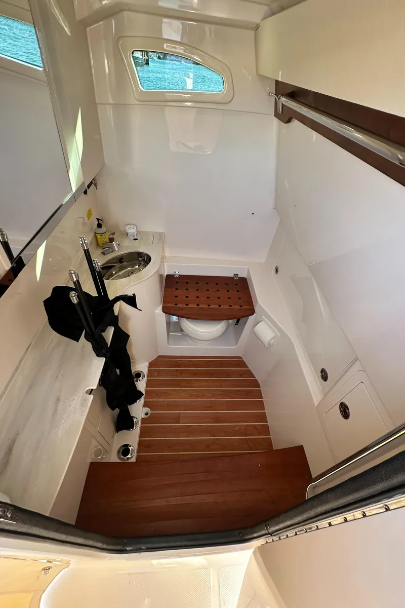 Slide: The Image of 2022 Grady-White Canyon 326 boat interior with compact bathroom and wooden flooring. - 47