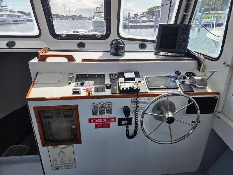 Slide: The Image of The helm of a 1998 BHM boat, featuring modern navigation equipment and a steering wheel. - 17