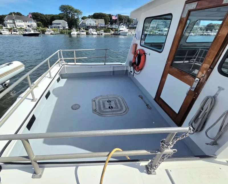Slide: The Image of The image shows the deck of a 1998 BHM boat, finished by Wilbur Yachts, docked in a calm harbor. - 4