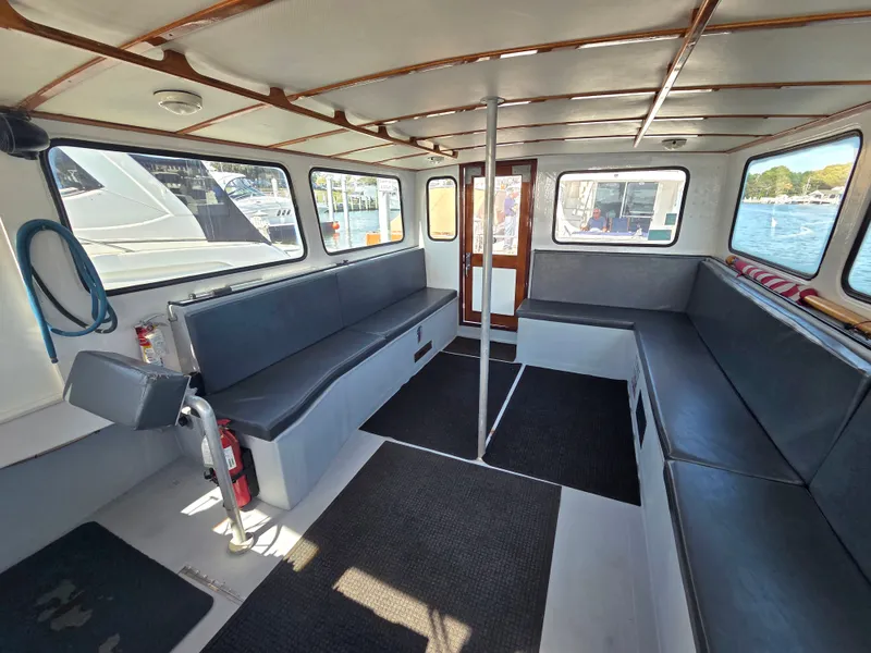 Slide: The Image of Interior of a 1998 BHM, finished by Wilbur Yachts, featuring gray seating and large windows. - 16