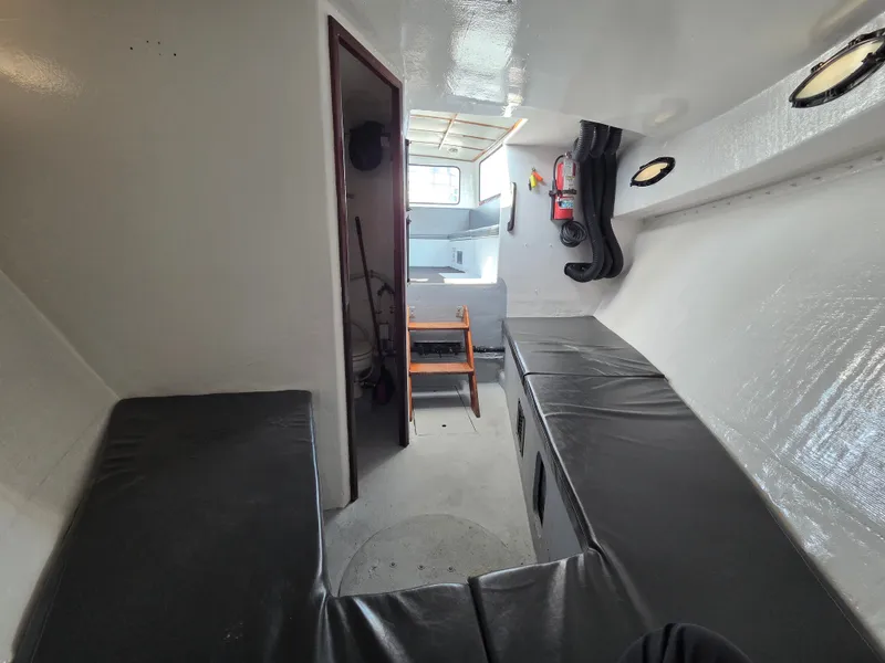 Slide: The Image of Interior of a 1998 BHM, finished by Wilbur Yachts, featuring cushioned benches and a small window. - 13