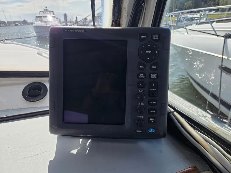 Slide: The Image of A navigation device on a boat, with other boats in the water in the background. - 21