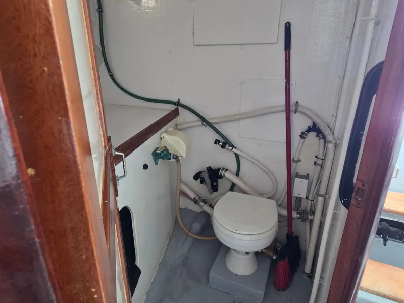 Slide: The Image of A small boat bathroom with a toilet, sink, and cleaning tools. - 14