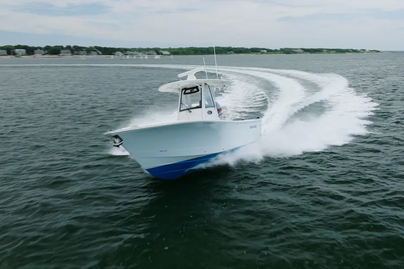 Slide: The Image of 2021 Regulator 28 Forward Seating boat cruising on open water, creating a dynamic wake. - 1