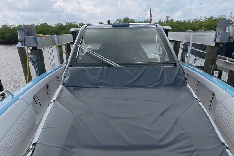 Slide: The Image of 2025 Schaefer V44 boat docked, covered with a protective tarp, under cloudy skies. - 56