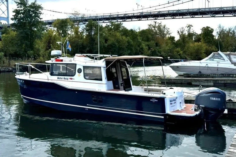 Slide: The Image of 2023 Ranger Tugs R-27 boat docked on a calm river under a bridge. - 49