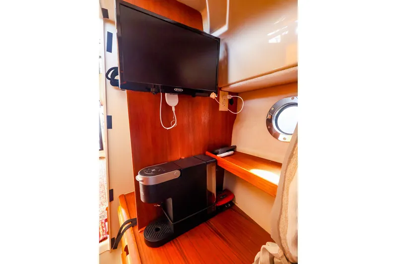 Slide: The Image of 2023 Ranger Tugs R-27 interior with TV and coffee maker setup. - 35