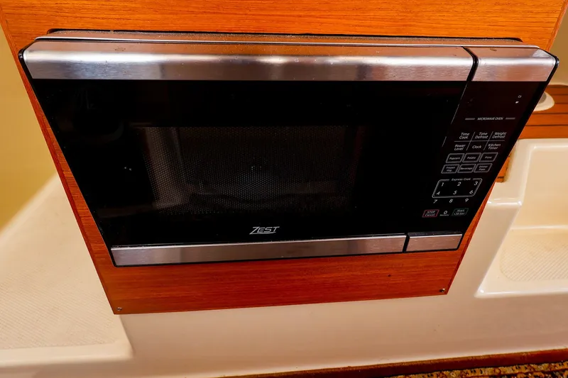 Slide: The Image of Microwave oven in 2023 Ranger Tugs R-27 boat interior, featuring wood paneling. - 23