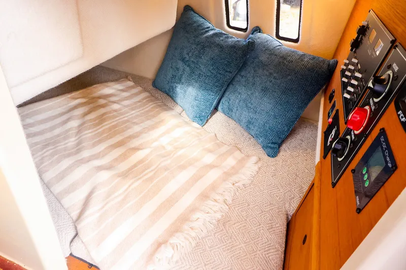 Slide: The Image of Cozy cabin interior of 2023 Ranger Tugs R-27 with striped bedding and control panel. - 43