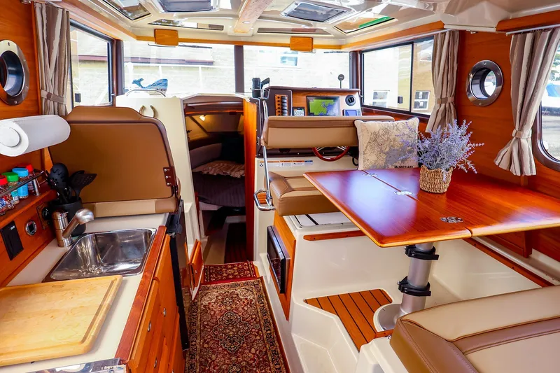 Slide: The Image of Interior of 2023 Ranger Tugs R-27 boat, featuring cozy dining and kitchen area. - 17