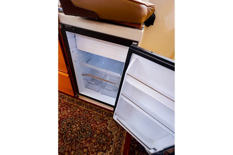 Slide: The Image of Open refrigerator inside 2023 Ranger Tugs R-27 boat, showcasing interior storage space. - 25
