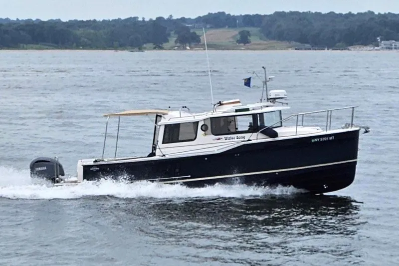 The Image of 2023 Ranger Tugs R-27 cruising on a scenic waterway with lush green shoreline. - 0